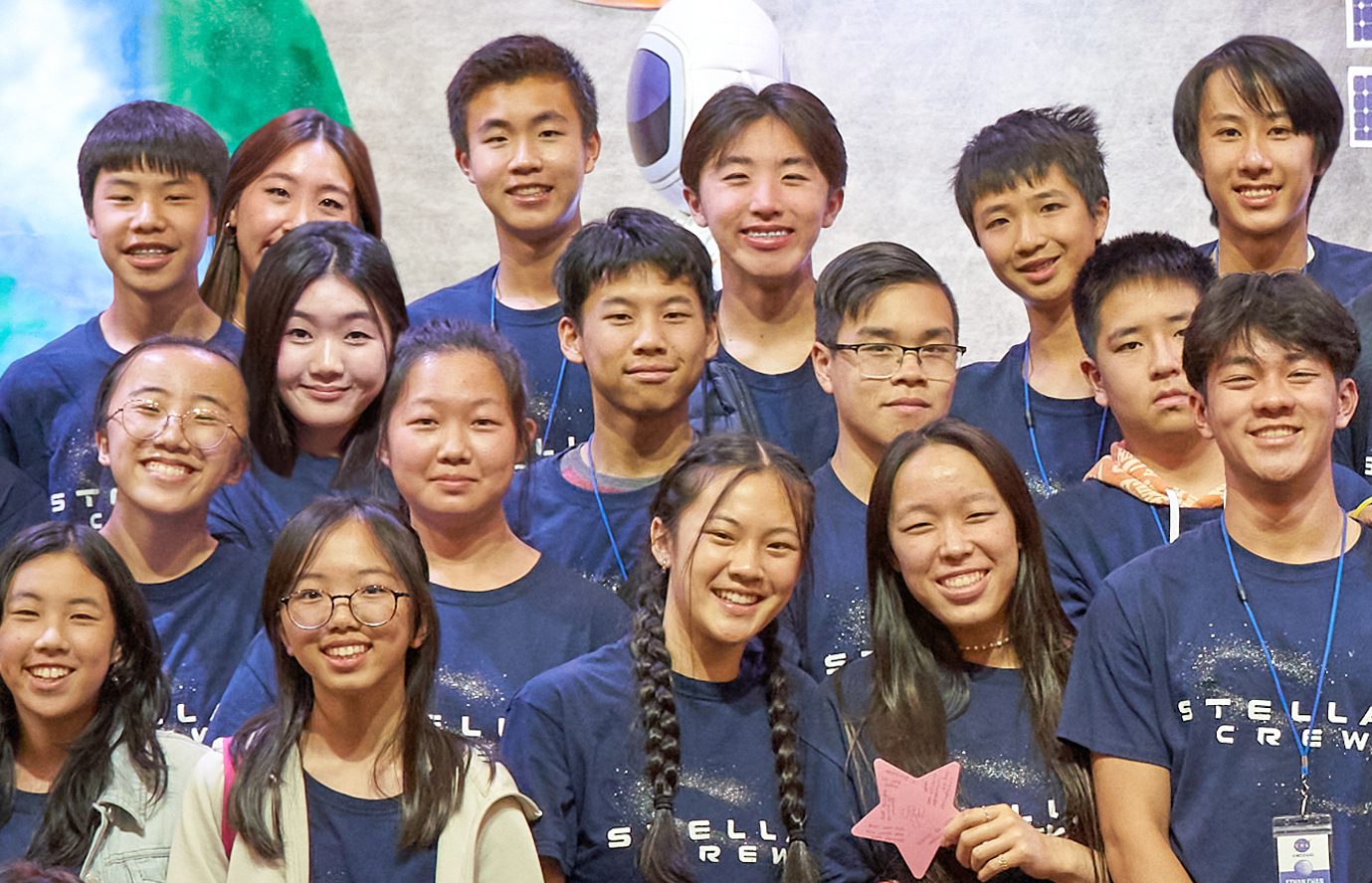 A group of smiling teenagers posing for a group photo indoors.