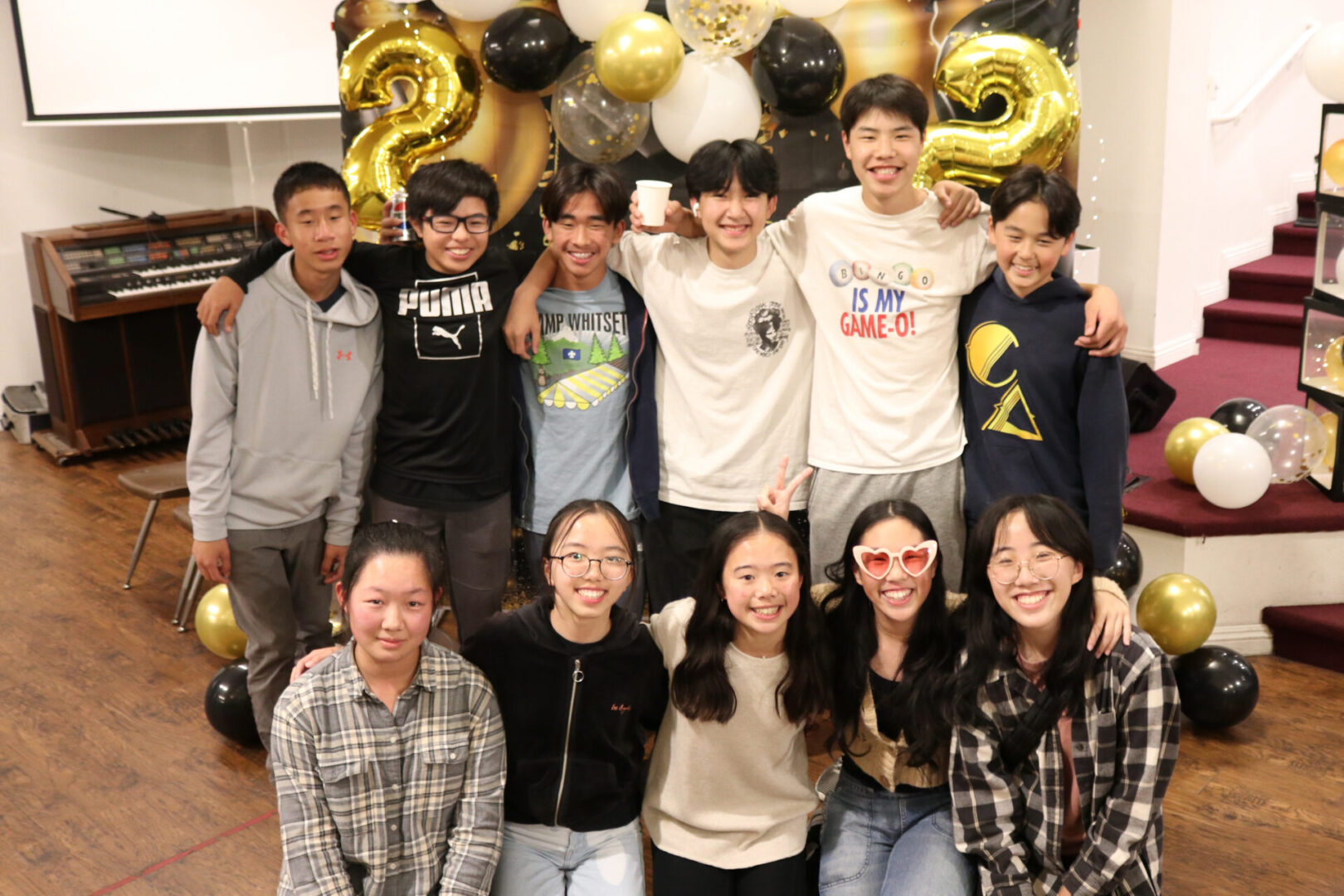 Group of smiling teenagers posing at a birthday party with balloons.